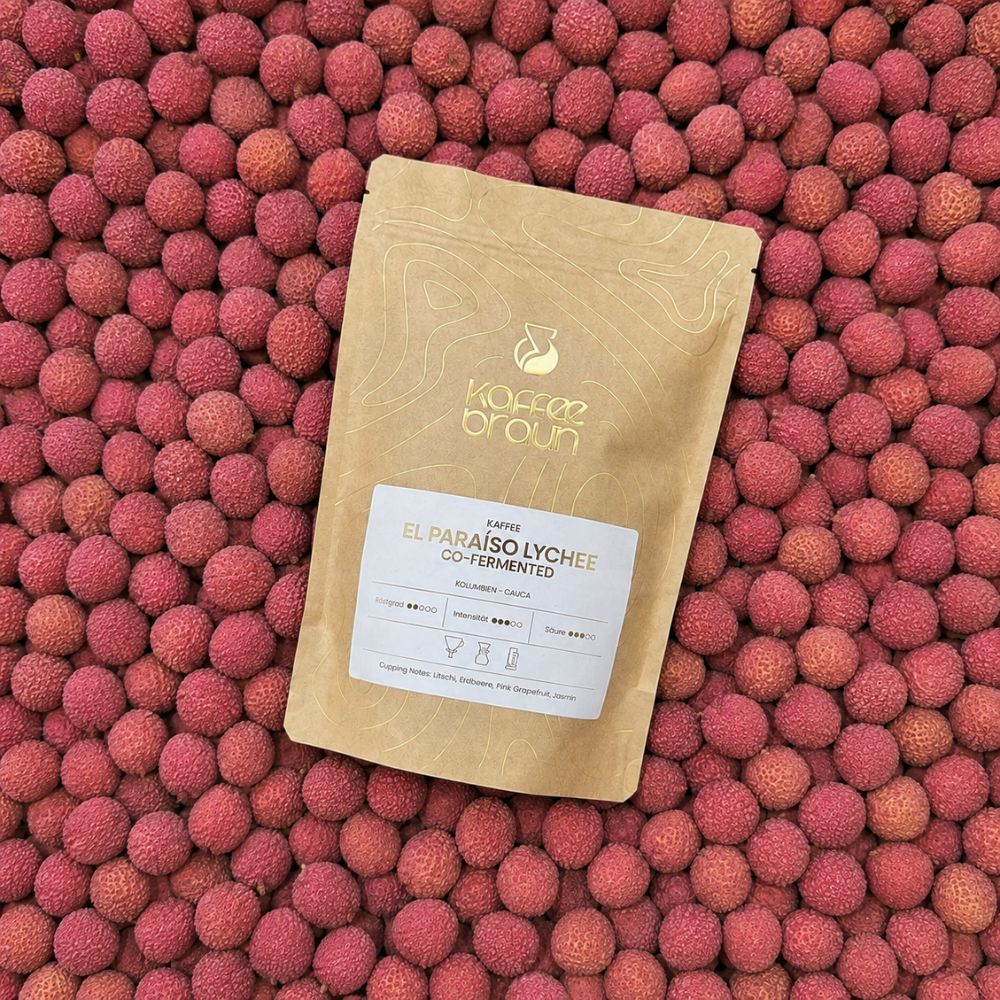 Packung El Paraíso Lychee Co-fermented liegt auf einem Bett aus frischen Litschis