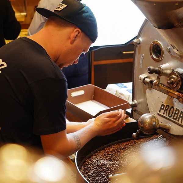 Mitarbeiter steht am Spezialitätenröster und betrachtet Kaffee in seiner Hand