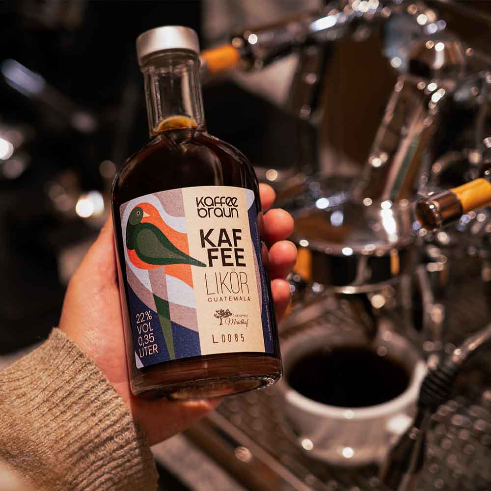 Kaffeelikör Flasche mit Kaffeelikör wird von Espressomaschine gehalten